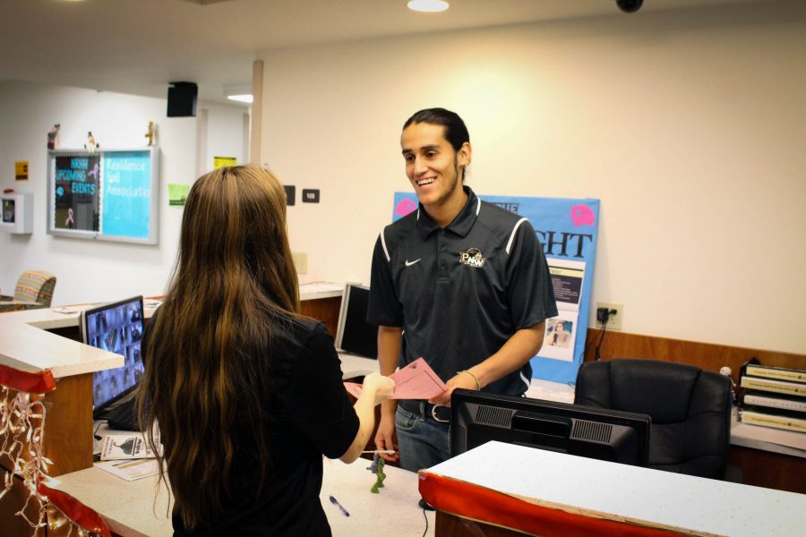 Sergio Reyes, team captain and mechanical engineering major, helps a student during his job as a resident assistant at the University Village.
